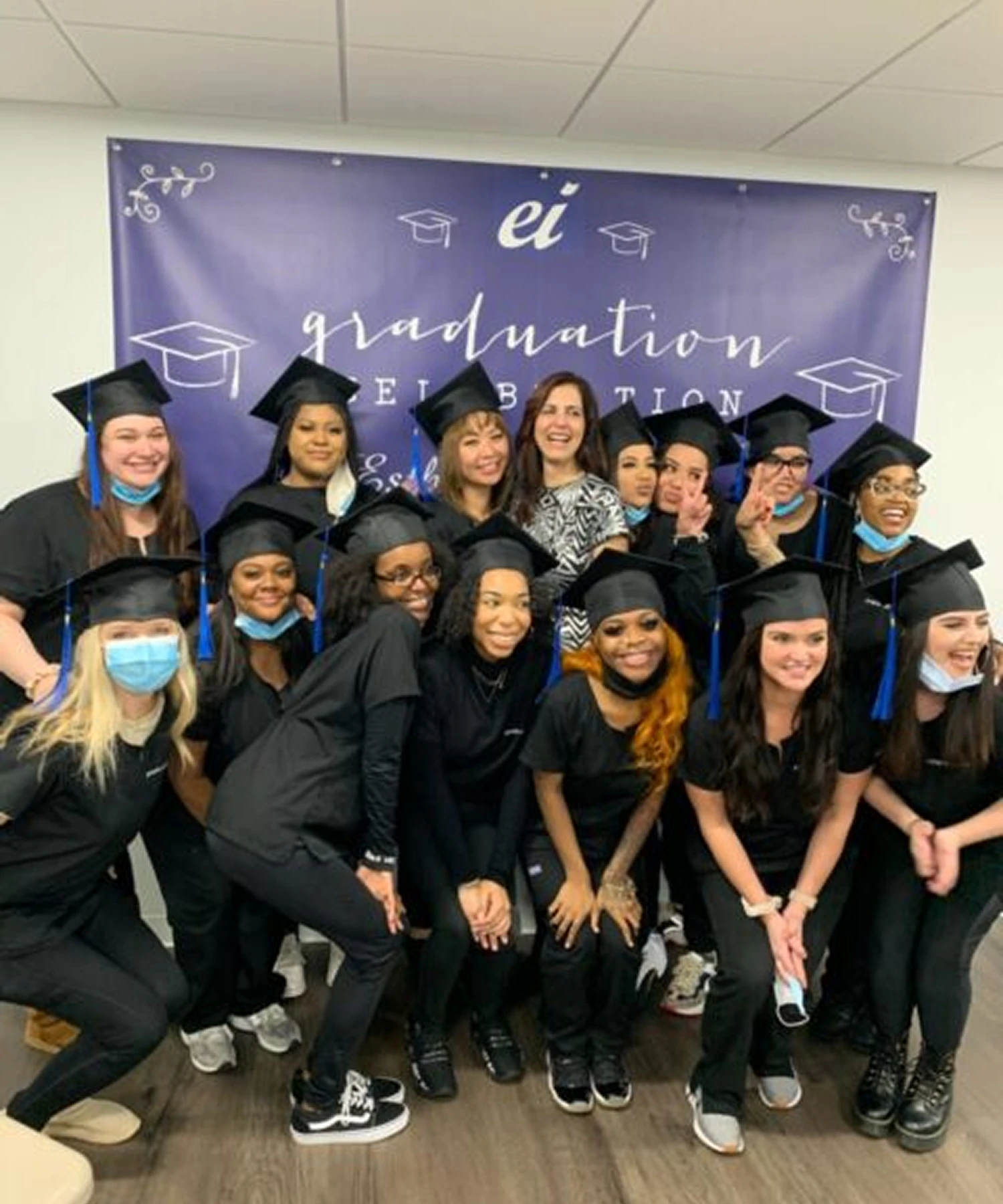 A group of graduates in black caps and gowns pose for a photo in front of a graduation banner.